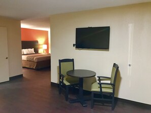 Una habitación de hotel con cama, televisor montado en la pared y una pequeña mesa con dos sillas.