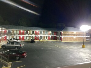 A motel with a two-story structure, a parking lot with several cars, and a well-lit exterior.