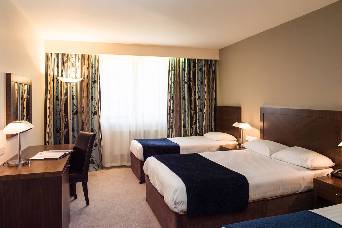A hotel room with two beds, a desk, and a chair.