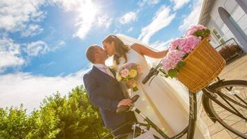 Una pareja de novios besándose frente a una bicicleta con una cesta de flores.