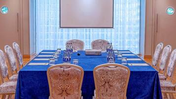 A conference room with a long table, chairs, a projector, and a screen.