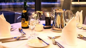 A table set for dining with a bottle of champagne, glasses, and cutlery. - Ballyroe Lodge (Tralee)