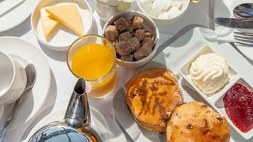 Un desayuno con platos de comida, incluyendo bollería, un vaso de zumo de naranja y un tazón de cubitos de azúcar.
