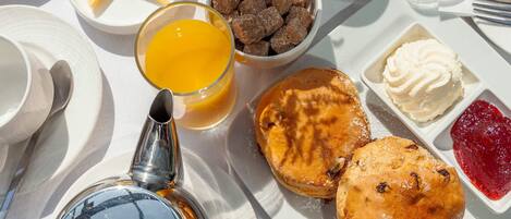 Un desayuno con platos de comida, incluyendo bollería, un vaso de zumo de naranja y un tazón de cubitos de azúcar.