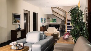 A modern living room with a staircase, leather sofas, a coffee table, and a large plant. - Ballyroe Lodge (Tralee)