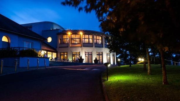 A modern building with a curved facade, large windows, and a well-lit entrance area. - Ballyroe Lodge (Tralee)