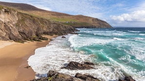 A coastal landscape with a sandy beach, rocky cliffs, and the ocean. - Ballyroe Lodge (Tralee)