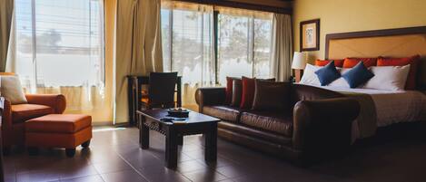 A hotel room with a bed, a sofa, a coffee table, and a chair.