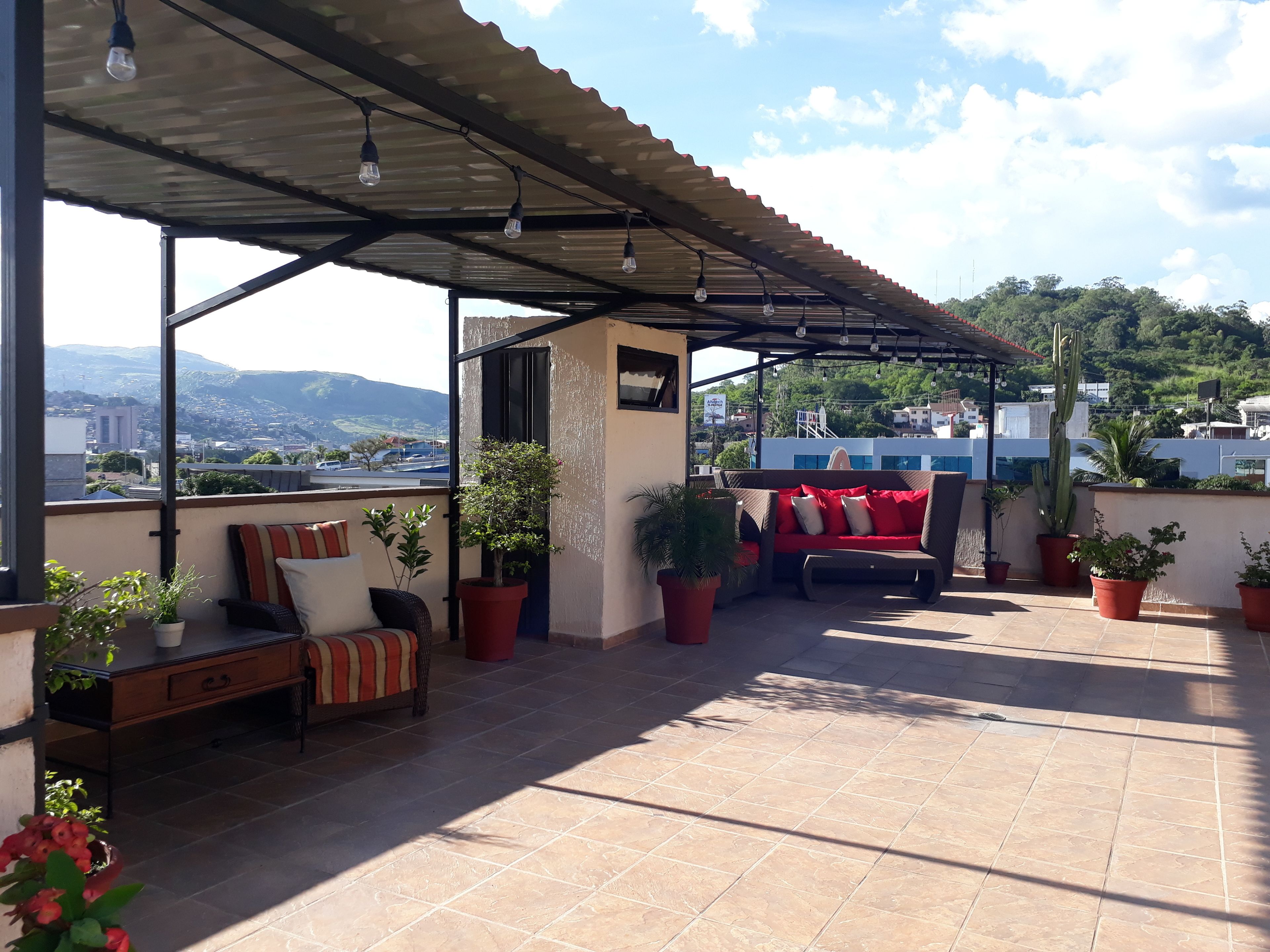 A covered outdoor seating area with a view of a cityscape and hills.
