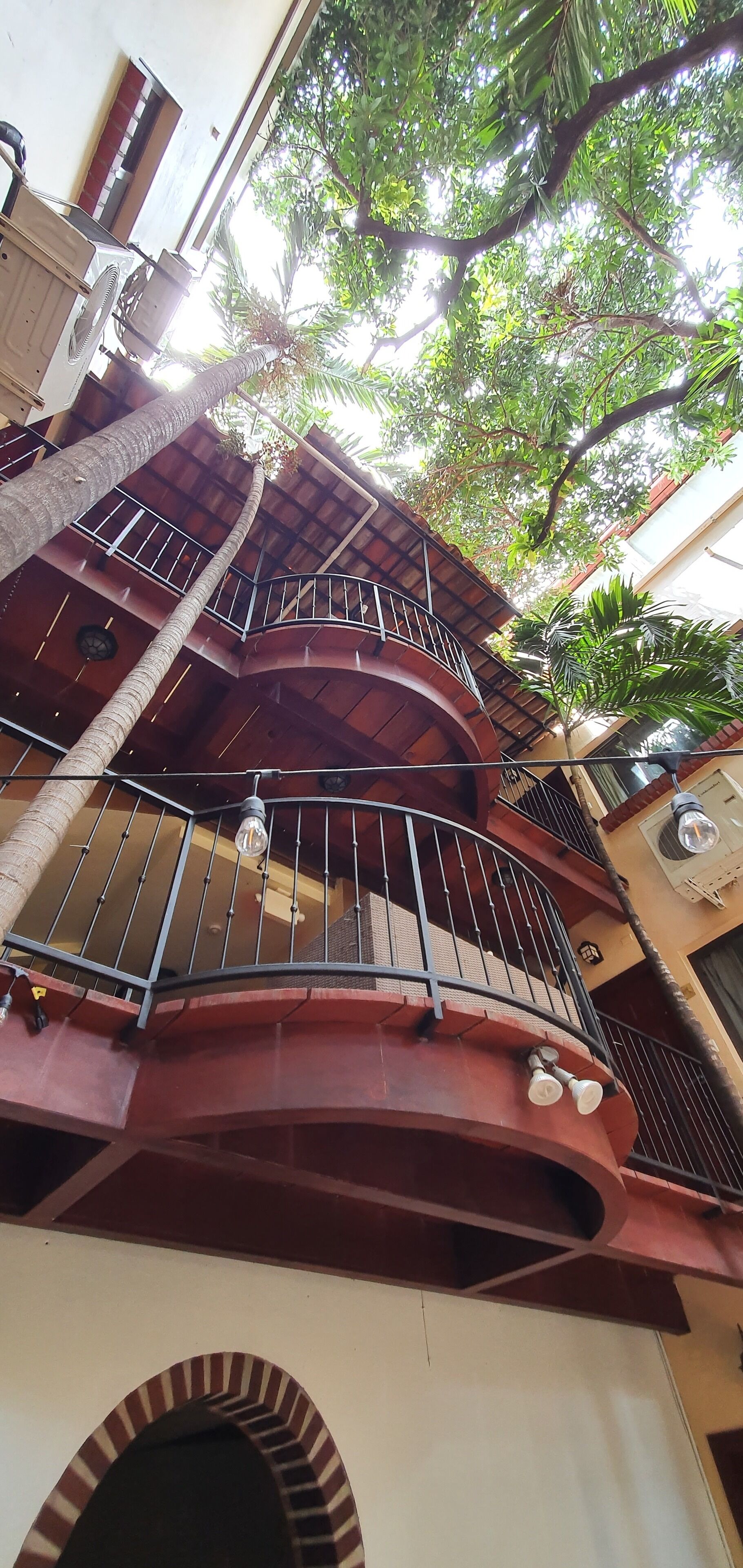 Ein mehrgeschossiges Gebäude mit geschwungenen Balkonen, einer zentralen Treppe und Blick auf umliegendes Grün.