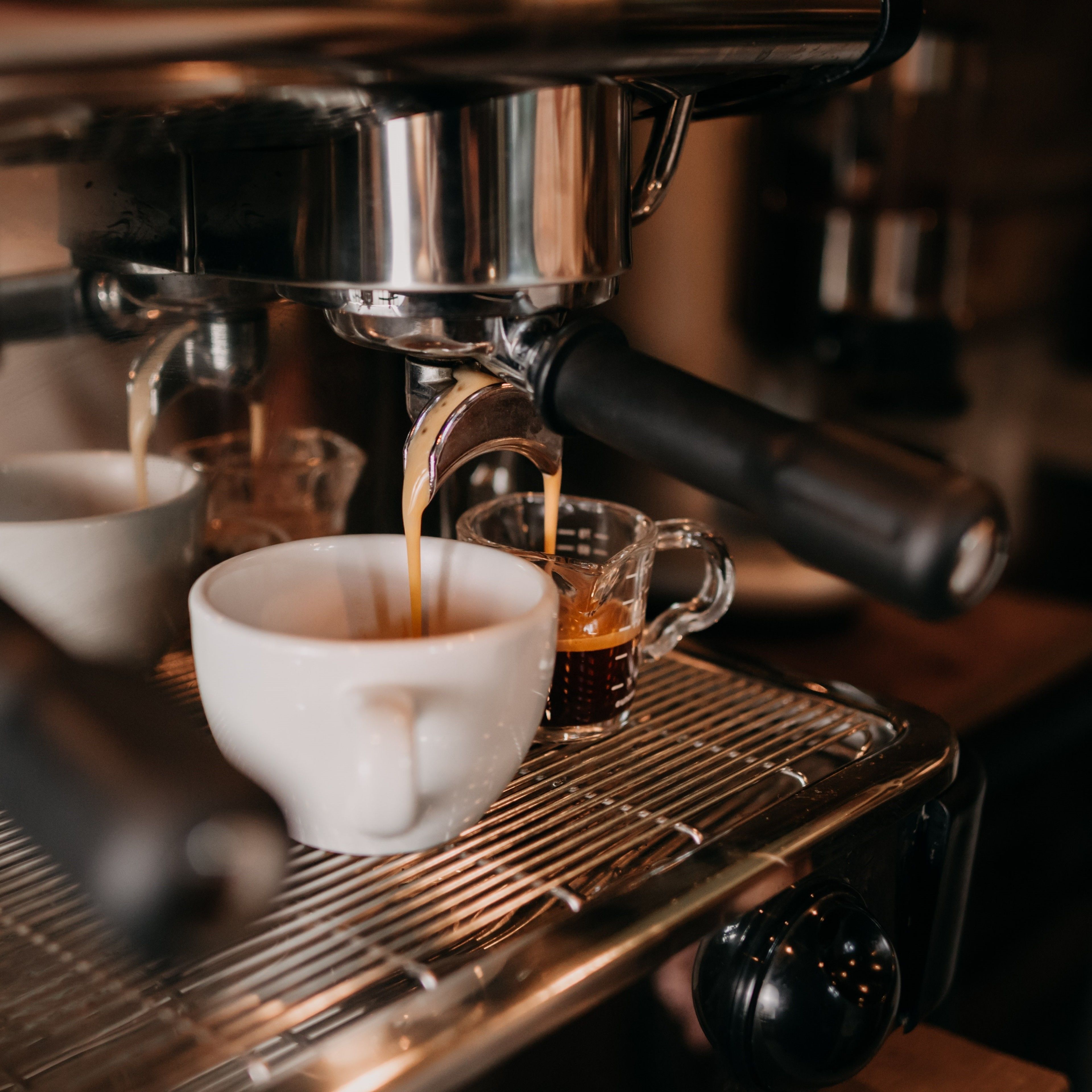 A coffee machine dispensing espresso into two cups.