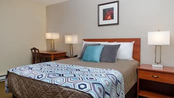 Una habitación de hotel con cama, mesitas de noche, escritorio y una silla.