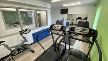 Un gimnasio con cintas de correr, bicicleta estática y un espejo.