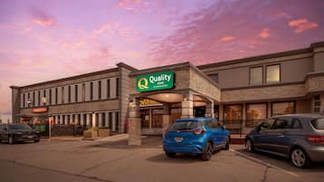 A hotel with a sign reading "Quality Inn by Choice Hotels" and a "Convenience Store" sign. There are two cars parked in front.