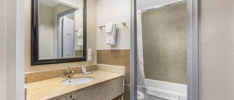 A bathroom with a sink, mirror, towel rack, and shower.