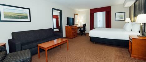 A hotel room with a bed, a sofa, a desk, a TV, and a chair.