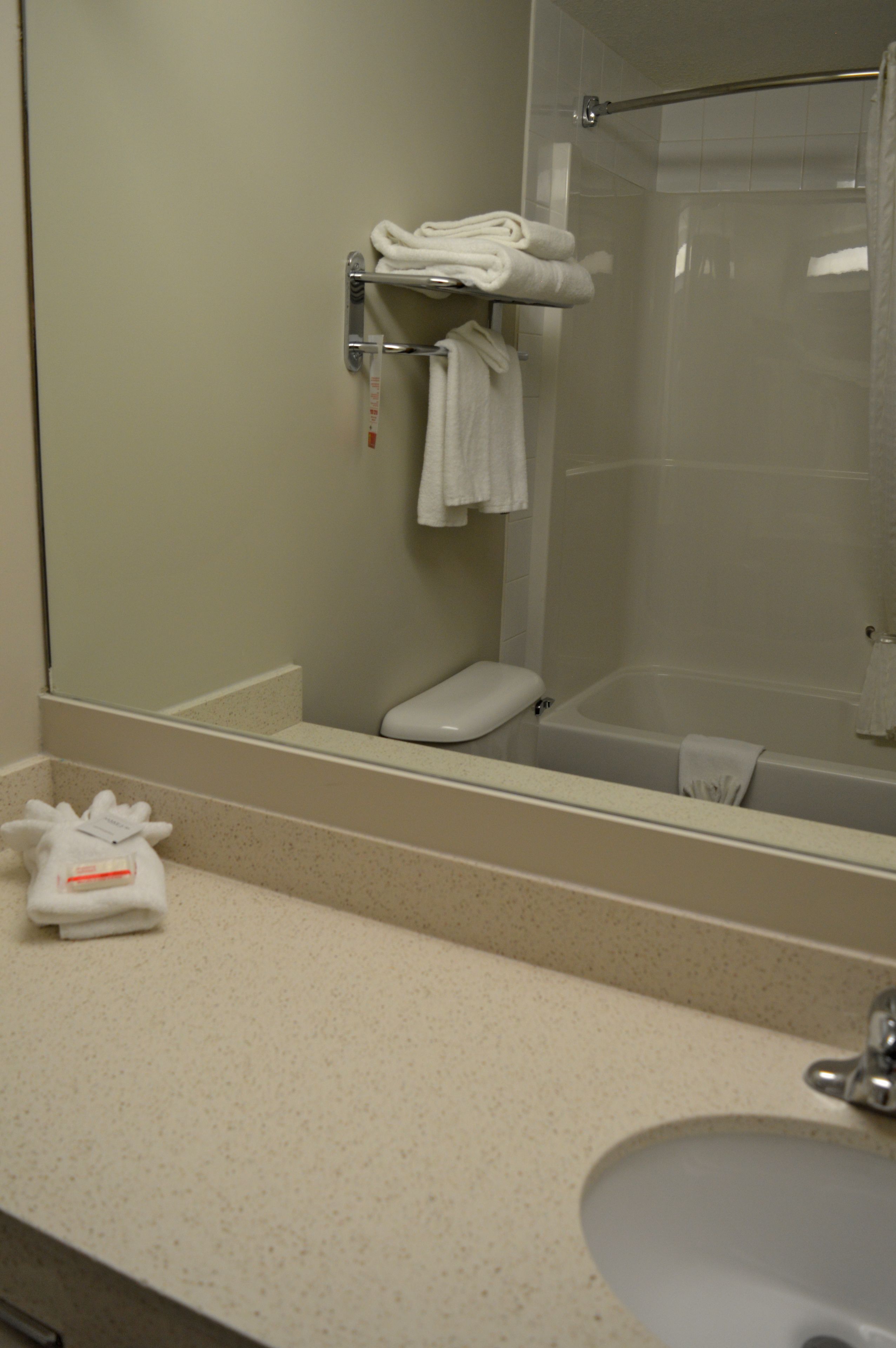 A bathroom with a toilet, a bathtub, and a sink. There are towels on a rack and a towel on the counter.