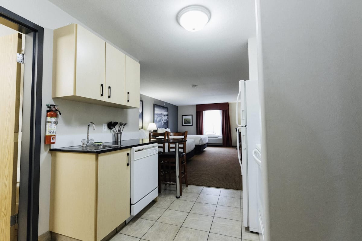 A compact hotel room with a kitchenette, a dining area, and a bed.