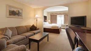 A hotel room with a sofa, a bed, a television, and a desk. - Border Inn and Suites Lloydminster (Lloydminster)