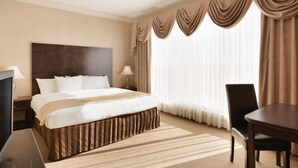 A hotel room with a large bed, a TV, a desk, and a chair. - Border Inn and Suites Lloydminster (Lloydminster)