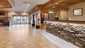 A spacious lobby with a stone accent wall, a reception desk, and a fireplace. - Border Inn and Suites Lloydminster (Lloydminster)