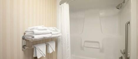 A shower with a glass door, a towel rack with folded towels, and a shower control panel.