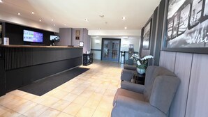 A reception area with a counter, seating, and a wall with a framed picture. - Super 8 by Wyndham Whitecourt (Whitecourt)