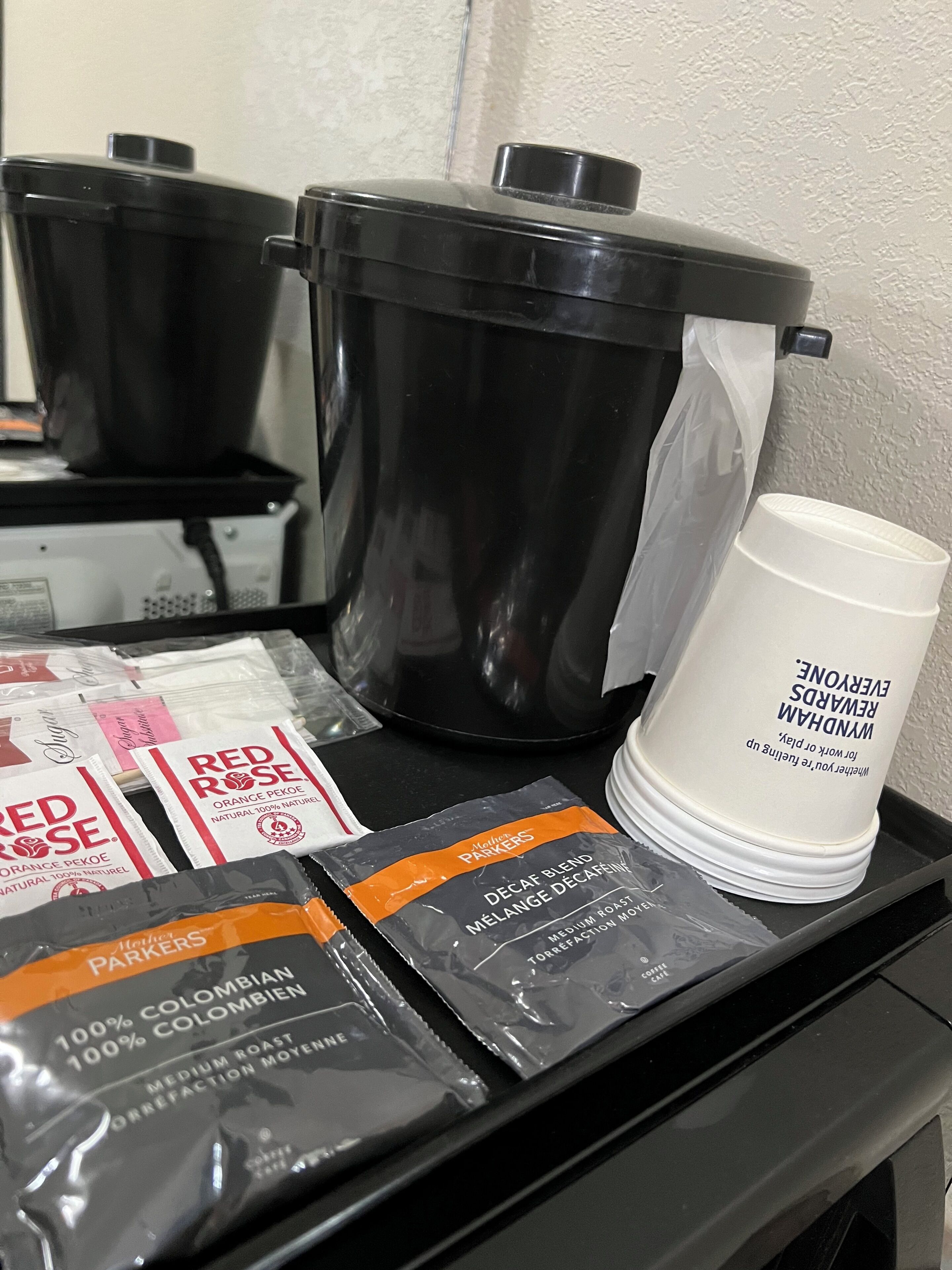 A kitchen area with a coffee maker, a coffee cup, and packets of coffee.