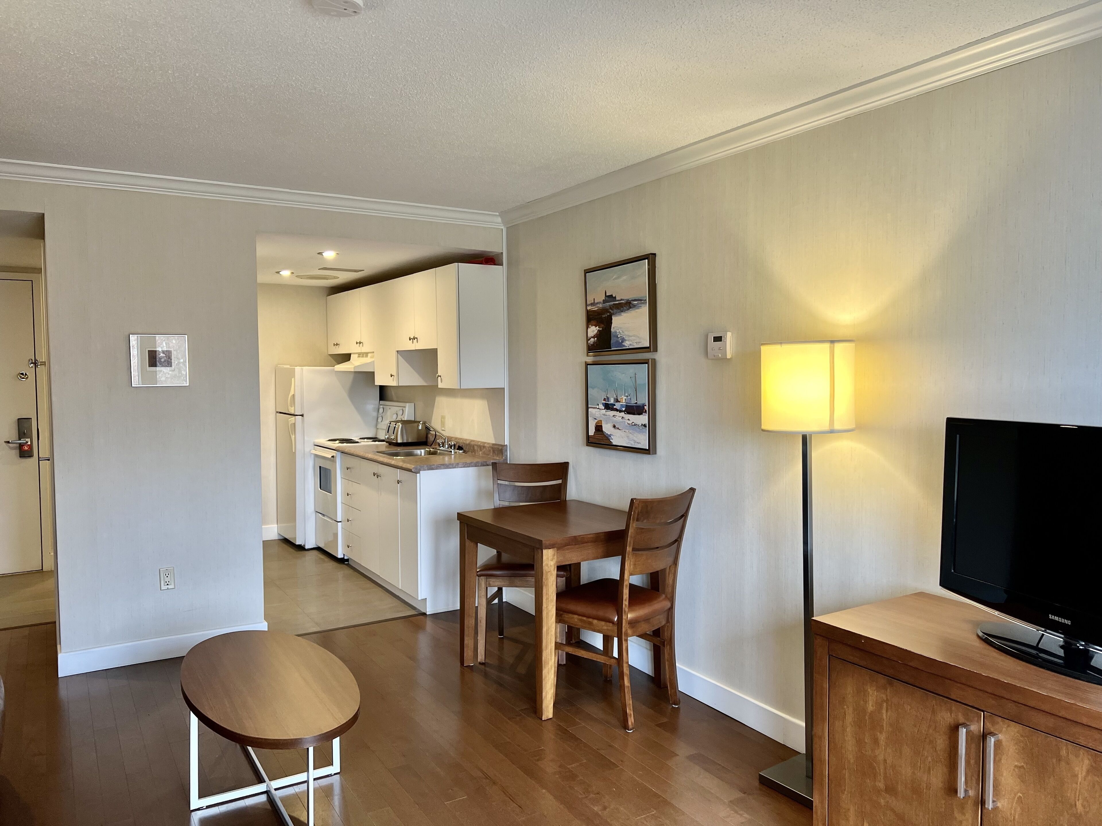 A compact living space with a kitchenette, dining area, and a TV on a wooden cabinet.