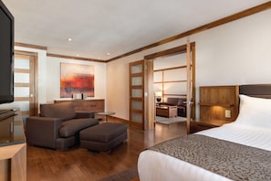 Habitación de hotel con cama, dos sillones, una mesita, un escritorio y un cuadro abstracto grande en la pared.