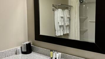 Une salle de bain avec un grand miroir, un lavabo et une douche.