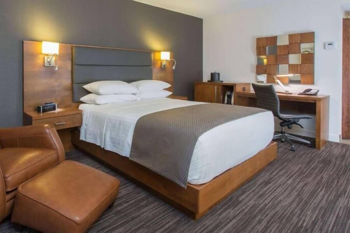 A hotel room with a bed, a desk, a chair, and a small table.