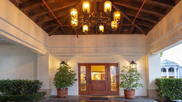 A covered entrance with a wooden ceiling, a chandelier, and potted plants. - Clocktower Inn Ventura (Ventura)