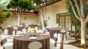 A restaurant with round tables, white chairs, and brown tablecloths. - Clocktower Inn Ventura (Ventura)