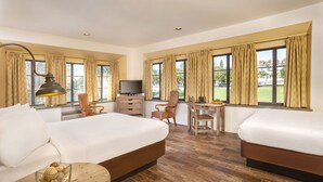 A hotel room with two beds, a desk, a TV, and large windows with curtains. - Clocktower Inn Ventura (Ventura)