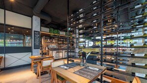 A modern interior with a wooden table and chairs, a wall-mounted wine rack, and a chalkboard menu. - PLAZA INN Blankenburg Ditzingen, Sure Hotel Collection (Ditzingen)