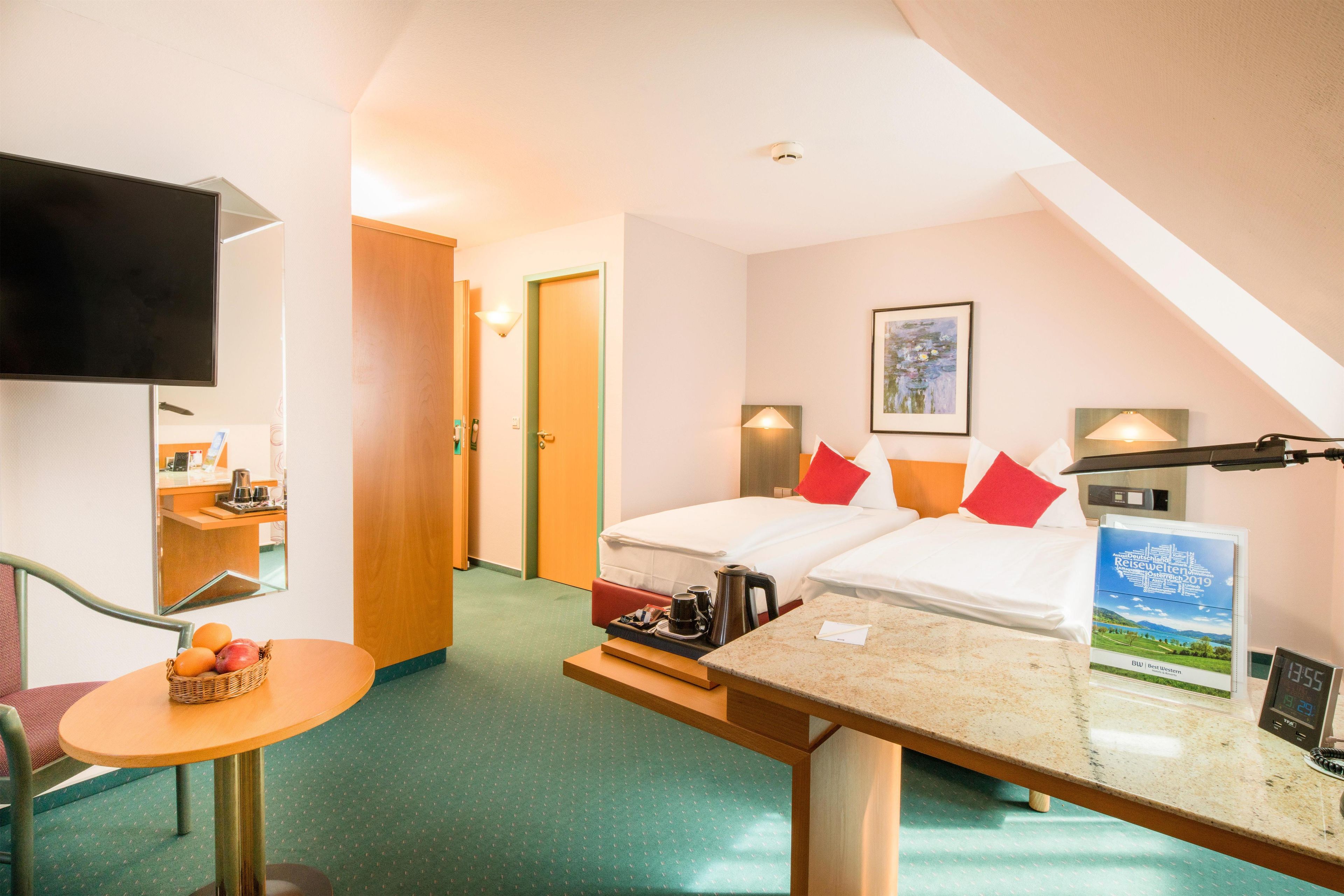 Una habitación de hotel con cama, escritorio, silla, televisión y un cuadro en la pared.