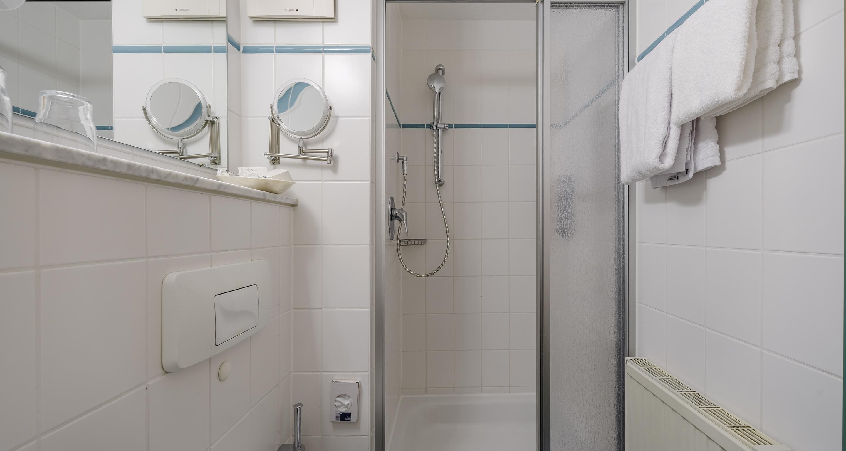A bathroom with a shower, a mirror, and a towel rack.