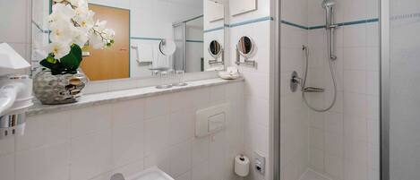 Ein Badezimmer mit Waschbecken, Toilette, Spiegel und Dusche.