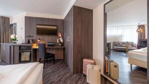 A hotel room with a bed, a desk with a computer, a TV, a minibar, and a large mirror reflecting the room. - PLAZA INN Blankenburg Ditzingen, Sure Hotel Collection (Ditzingen)
