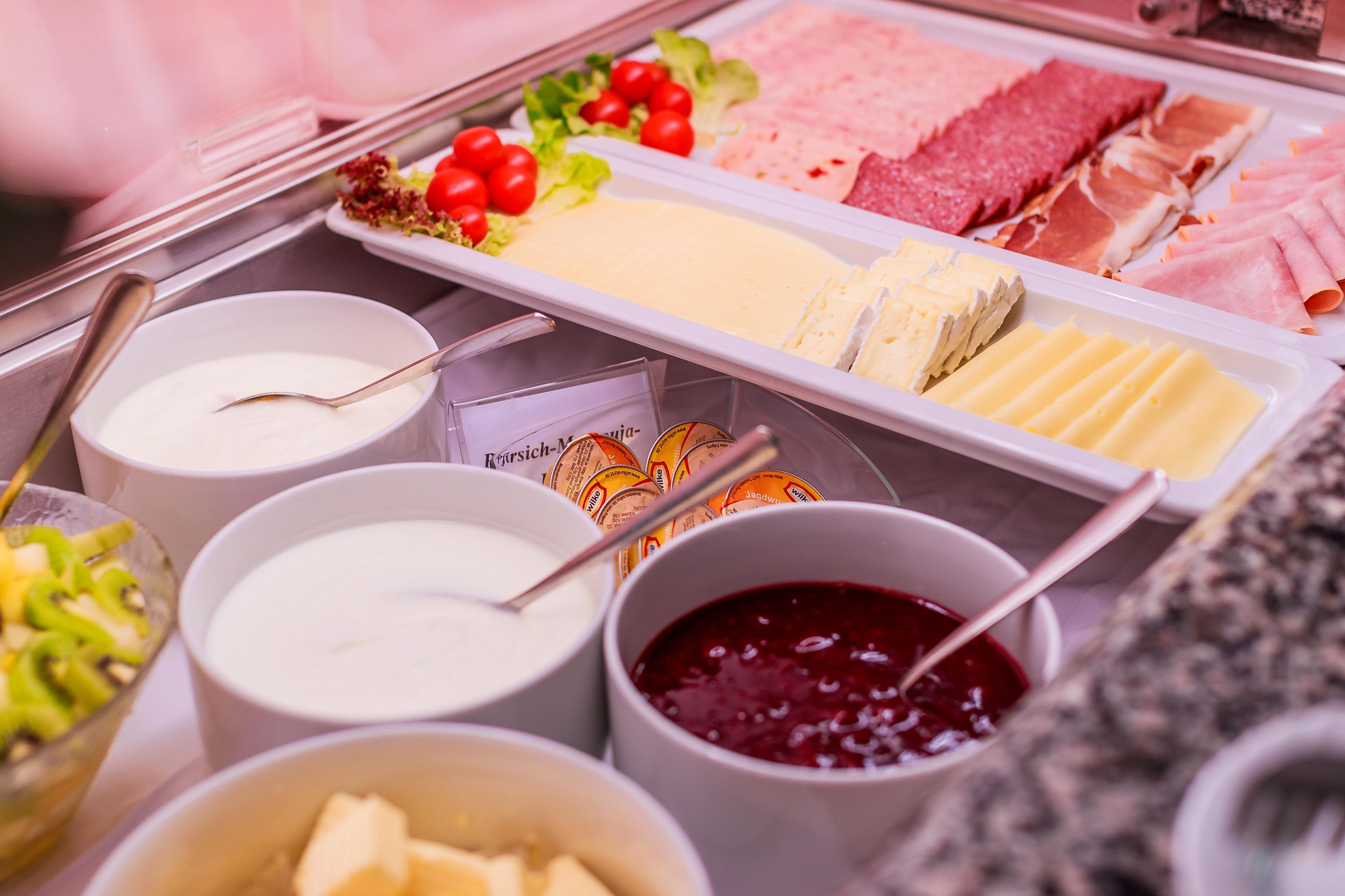 Un bufé con diversas opciones de comida, incluyendo carnes, quesos y salsas.