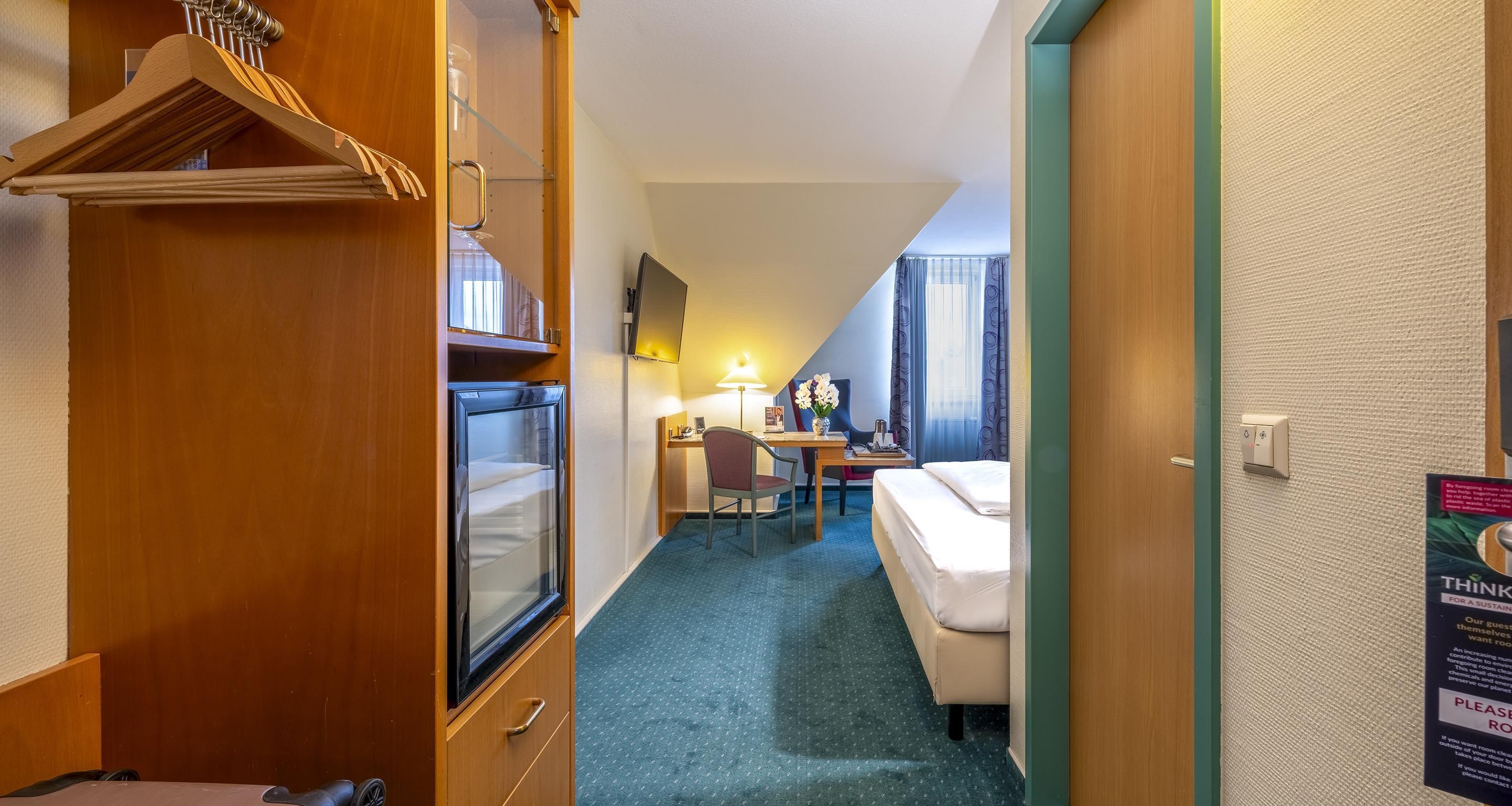 Una habitación de hotel con cama, escritorio, silla y armario.