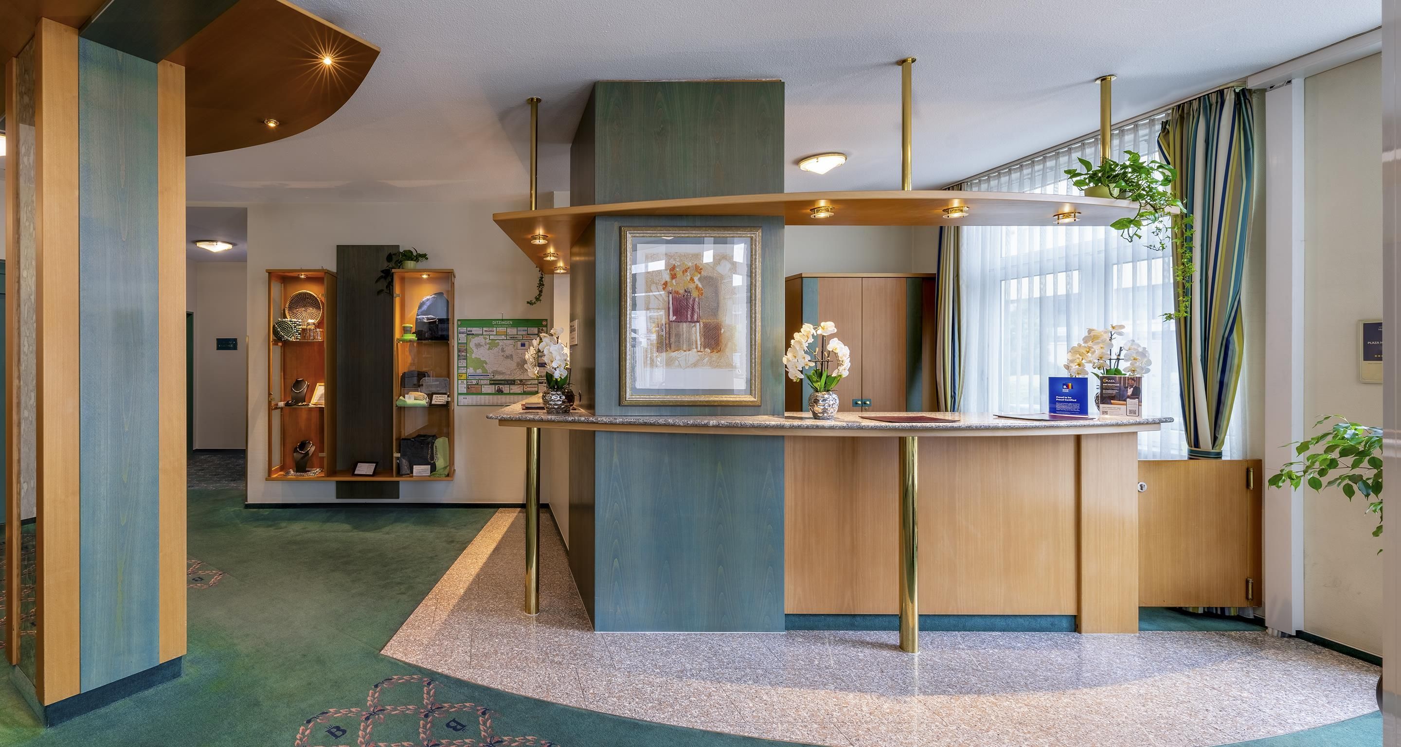A reception desk with a framed artwork, a map, and a plant.