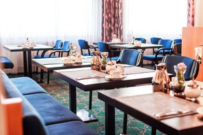 A hotel dining area with tables set for service, blue upholstered seating, and a patterned carpet. - PLAZA INN Blankenburg Ditzingen, Sure Hotel Collection (Ditzingen)