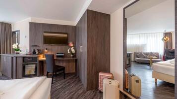 Ein Hotelzimmer mit einem Bett, einem Schreibtisch mit Computer, einem Fernseher und einem großen Spiegel, der den Raum widerspiegelt.