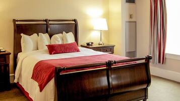 A neatly made bed with a wooden frame, two bedside tables with lamps, and a view of a window with curtains.