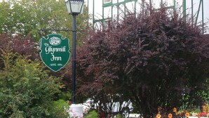 En traditionell byggnad med en skylt som visar namnet Glynnmill Inn, omgiven av en färggrann blomsterrabatt.
