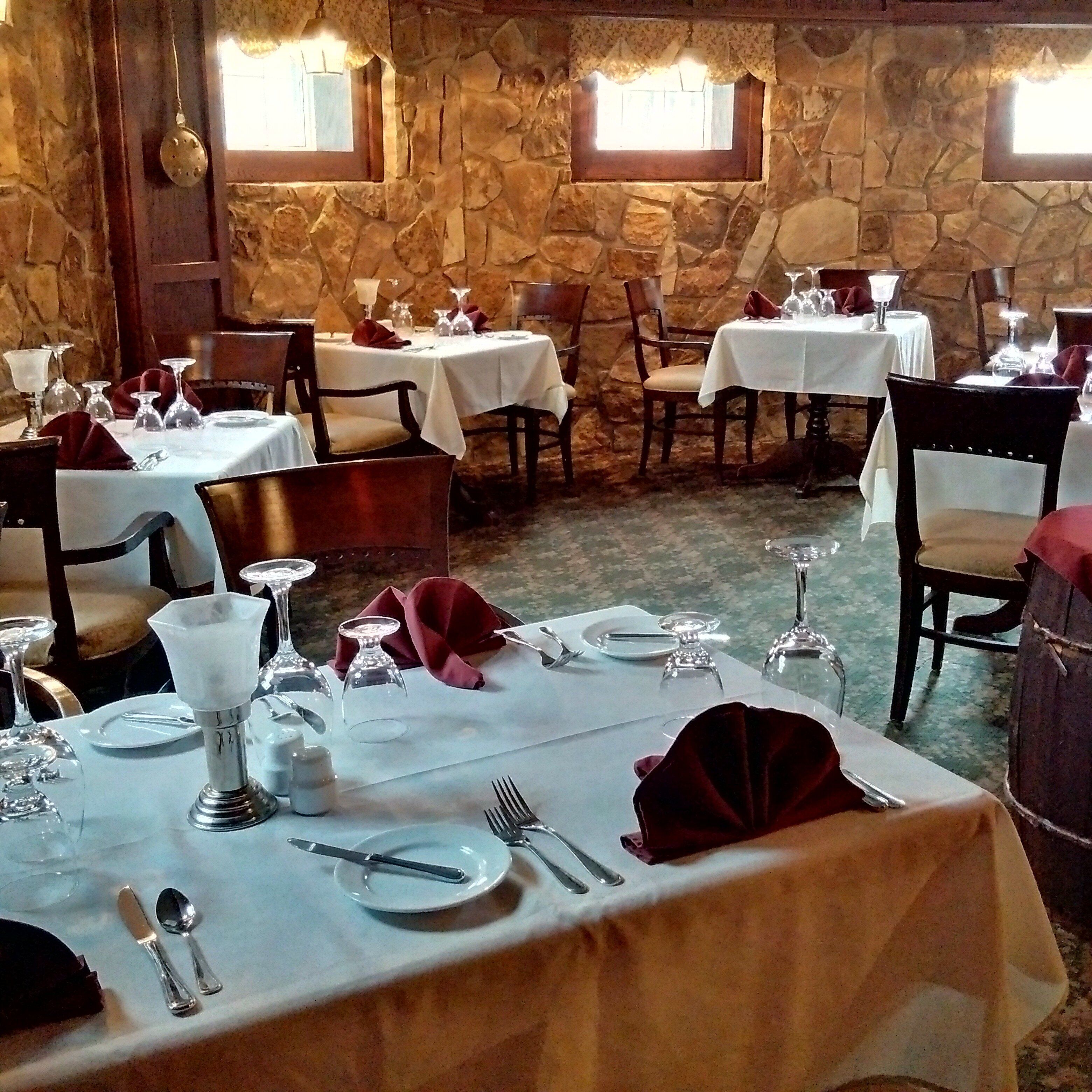 A restaurant with stone walls and multiple tables set for dining.