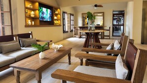 A spacious living room with a wooden coffee table, a sofa, and a dining area with wooden chairs and a table. - Hotel Sands Arenas (Mazatlán)