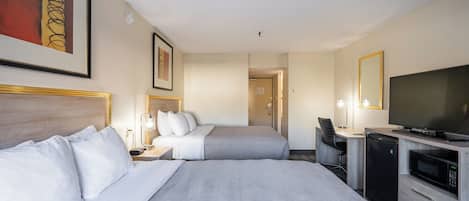 A hotel room with two beds, a desk, a television, and a microwave.